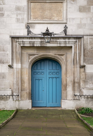 London, UK -â Dec 25, 2023 - Arched medieval door with a lantern above it. Details of Closed blue wooden church doorway in a gothic stone wall at City of Westminster, European style, Space for text, Selective focus.のeditorial素材