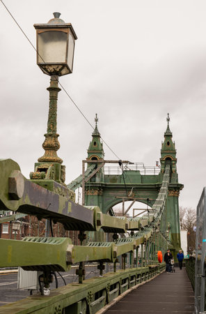 London, UK - Dec 25, 2023 - Traditional metal Hammersmith bridge for pedestrians and cyclists over the River thames. One of the world's oldest suspension bridges and a major river crossing and primary route in west london, Cast-iron bridge, Space for textのeditorial素材