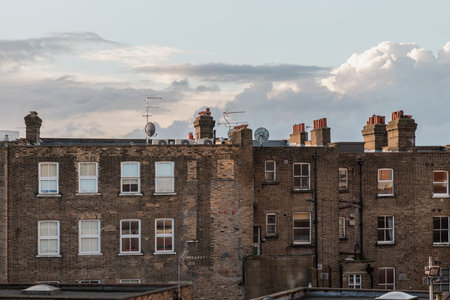 London, UK - Feb 18, 2024 - Rear view of urban brick apartment buildings and old houses in london with sky background at evening. Exterior of The Windows and decoration of walls, Space for text, Selective focus.のeditorial素材