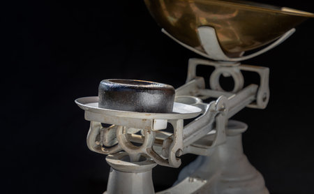 Cast iron weights on Old obsolete manual weighing scales and Iron Brass Tray on dark background. Classic weight scale, Antique balance scales, Space for text, Selective Focus.の写真素材