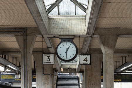 London, UK - Feb 27, 2024 - 1:31 p.m. on The station clock and platform number 3 and 4 indicators in the Acton Town station. Travel transportation, Space for text, Selective focus.のeditorial素材