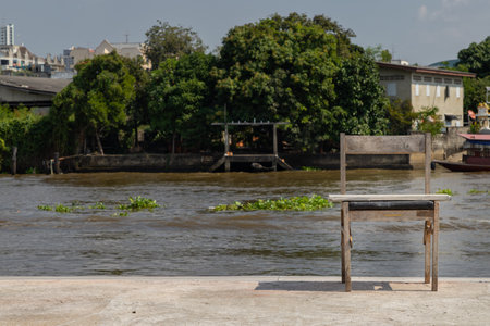 The old wooden chair is in front of the river, which is on the cement floor. Space for text, Selective focus.の写真素材