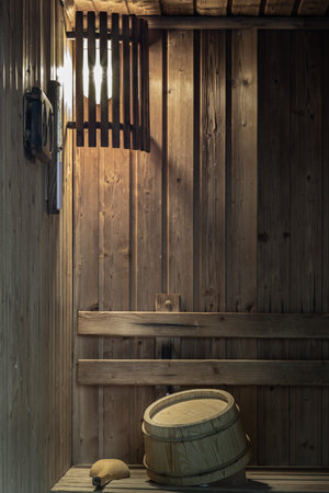 The space is warmly lit by a wall-mounted lamp, casting a cozy glow over the wooden bucket and ladle...
