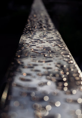 Detail of Water droplets caused by rain perched on the metallic surface. Rain water drops on a stainless steel handle, Natural Pattern of dew drops or raindrops on silver metal background for wallpaper poster and banner design, Selective focus.の写真素材