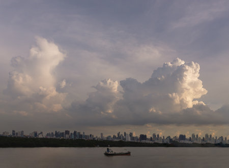 Bangkok, Thailand - 06 Aug 2024 - Beautiful Clouds in the Sky over Large Metropolitan City of Bangkok along Chao praya riverside with cargo ship. View of Skyscrapers and Dramatic Sky before Sunset, Space for text, Selective focus.のeditorial素材