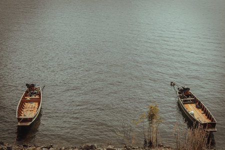 Two traditional hand built small wooden rowboat slowly in warm evening light was resting along in...