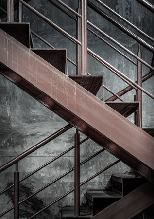 Vertical view of Old Steel ladder with handrails with concrete wall in the background. Side view of Metal steps, Dark tone, Copy space, Selective Focus.の写真素材