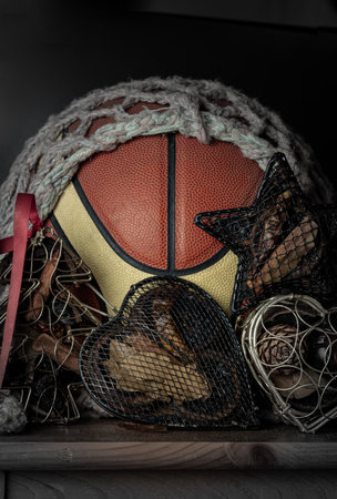 Basketball ball inside of mesh net string decoration with Christmas tree mesh case, Heart mesh case and Star mesh case on Dark background. Christmas-themed event basketball idea, sports play on christmas, use it as your Wallpaper, Poster and Space for text, Selective focus.の写真素材