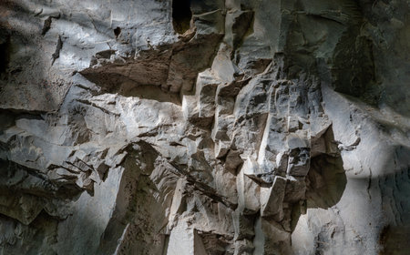 Elegance of The intricate natural light and shadow on surface of stone wall. Pattern of granite on the mountains that erode naturally, The sunlight shining through down to Limestone walls on the outside cave walls, use it as your Wallpaper, Poster and Copy space, Selective focus.の写真素材