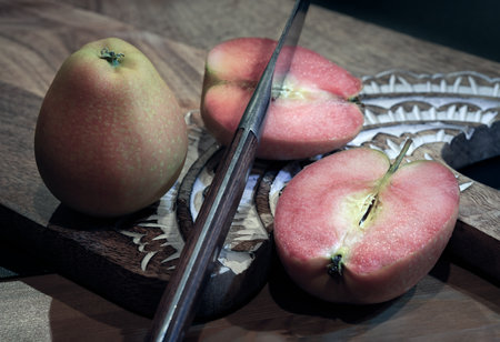 Fresh kissabel apple fruit and Cut the apple in each half with knife on wooden cutting board. Naturally pink flesh kissabel apple with a unique zesty taste, Copy space, Selective Focus.の写真素材