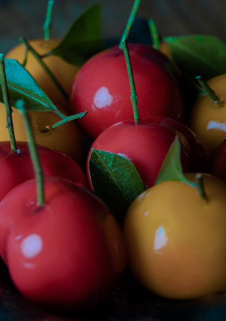 Detail of Colorful imitation fruits (Kanom look choup) in the shape of oranges, rose apple and strawberries has a sweet taste. Traditional thai sweet treats made from mung beans and coconut milk, and glazed in shiny agar agar jelly. Use it as your Wallpaper, Poster and Space for text, Selective focus.の写真素材