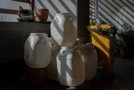 Morning sunlight shines through Wooden Battens with hitting on white plastic drums piled near the...