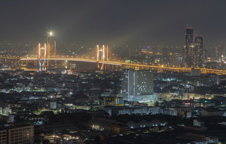 Bangkok, Thailand 31 Dec, 2024 - Nightscape view of Skyscrapers with Thotsamarachan Bridge (Rama IX Bridge) crossing Chao phraya river. Beautiful city of Bangkok with bright glowing lights, use it as your Wallpaper, Poster and Space for text, Selective focus.の写真素材