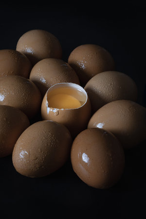 View of Egg yolk in Broken raw chicken eggshell in the among of Fresh chicken egg (Hen egg) on dark background. Natural organic fresh eggs for healthy food, use it as your Space for text, Design, Wallpaper and Poster, Selective focus.の写真素材