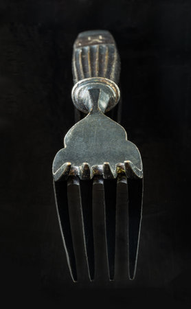 Perspective surface view of vintage fork isolated on black background. Close-up of worn metal...