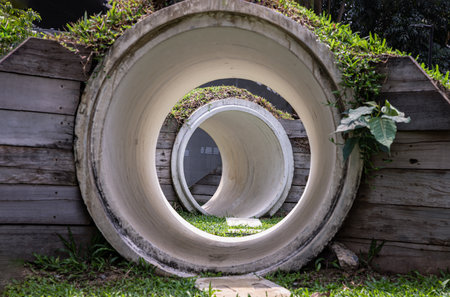 Park concrete tunnel made for Children's play as a rabbit, ducking through its numerous burrows. Outdoor playground with The kid's playing tunnel with Grass mound on top in the park for children.の写真素材
