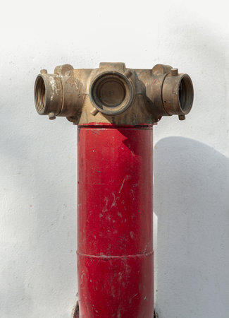 Red fire hydrant with Brass valve for Fire anticipation on land in front of an on white cement wall background. Fire Department Connections, Fire safety concept, use it as your Wallpaper, Poster and Space for text, Selective focus.の写真素材