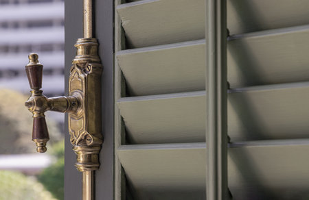 Bangkok, Thailand - Mar 02, 2025 - View of Antique brass window bolts or window lock handle on Green wooden louvered window shutters. use it as your Wallpaper, Poster and Space for text, Selective focus.の写真素材