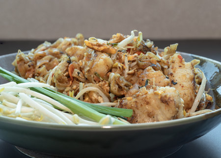 Traditional fried thai noodle (pad thai) mix Stirred fried turnip cake or Fried radish cake (chai tow kway) served with bean sprout and chives in ceramic plate. use it as your Space for text, Design, and Poster, Selective focus.の写真素材