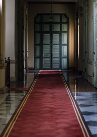 Bangkok, Thailand - Mar 02, 2025 - Perspective hallway leading into green wooden door inside The main Bang Khun Phrom Palace that blends Baroque style with stucco designs.の写真素材