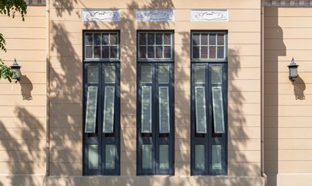 Bangkok, Thailand - Mar 02, 2025 - The Sunlight shines through Multiple green wooden louvered window shutters on cement wall of The Bang Khun Phrom or Bank of Thailand Museum is a magnificent. early 20th century European style palace in neo-Baroque / Rococo style combined German Art Nouveau style, use it as your Wallpaper, Poster and Space for text, Selective focus.の写真素材
