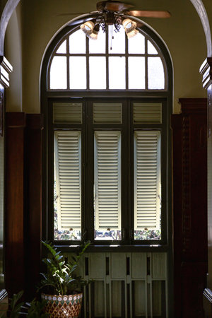 Bangkok, Thailand - Mar 02, 2025 - View of Three wooden louvered window shutters under glass frame inside of Hallway with Vintage ceiling fan and lights inside The main Bang Khun Phrom Palace or Bank of Thailand Museum that blends Baroque style with stucco designs. use it as your Wallpaper, Poster and Copy space, Selective focus.の写真素材