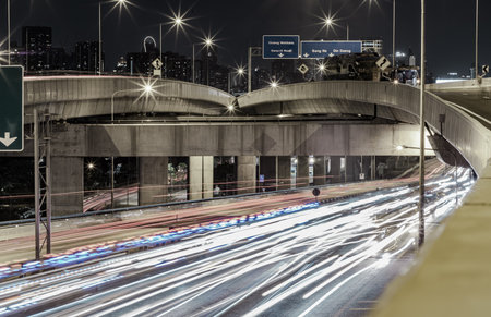 Bangkok, Thailand - Jan 10, 2025 - A nightscape view with bright glowing light trails effect of many cars headlights and rear lights on urban expressway of Bangkok. Long exposure for Light curve lines, use it as wallpaper, Poster and Copy space, Selective focus.の写真素材