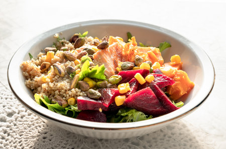 Delicious Quinoa Salmon Poke bowl garnished with Leaves salad, Beetroot, Sweet potato, Sweet corn and Pistachio on Ceramic bowl. use it as your Wallpaper, Poster, Design and Space for text, Selected focus.の写真素材