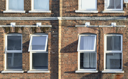 London, UK - Apr 06, 2025 - The sunshine lights through the glass window frame exterior of old house. Glass window and brick wall in London, use it as your Wallpaper, Poster and Copy space, Selective focus.の写真素材