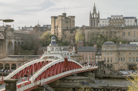 Newcastle, UK - Apr 11, 2025 - A view of the Swing bridge or Swing span bridge spanning the River Tyne with historical buildings at the background in Newcastle Upon Tyne in the North East of England. The pedestrian bridge, Selective focus.の写真素材