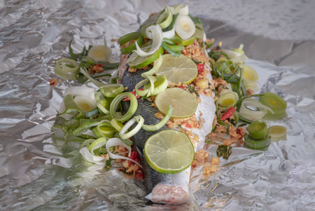 Prepare Whole Baked Salmon with Herbs on aluminium foil. ingredient include Coriander root, Ginger, Galangal, Kaffir lime, Leek, chopped together and Bird's eye chili with Slice lemons place on the Salmon fish. Healthy eating, use it as your Wallpaper, Poster and Space for text, Selective focus.の写真素材