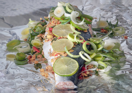 Prepare Whole Baked Salmon with Herbs on aluminium foil. ingredient include Coriander root, Ginger, Galangal, Kaffir lime, Leek, chopped together and Bird's eye chili with Slice lemons place on the Salmon fish. Healthy eating, use it as your Wallpaper, Poster and Space for text, Selective focus.の写真素材