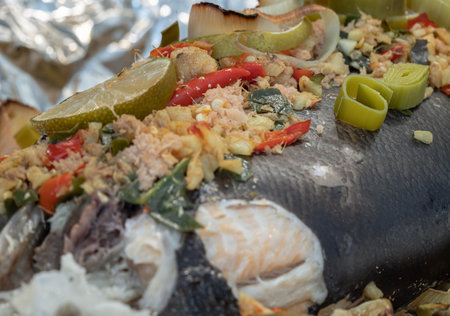 Close-up of Baked Salmon with Herbs, ingredient include Coriander root, Ginger, Galangal, Kaffir lime, Leek, chopped together and Bird's eye chili with Slice lemons place on the Salmon fish. Healthy eating, use it as your Wallpaper, Poster and Copy space, Selective focus.の写真素材