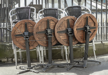 Wooden tables and Stainless steel chairs piled up along the Iron fence next to the walkway front of Pub & Restaurant. use it as your Wallpaper, Poster and Space for text, Selective focus.の写真素材