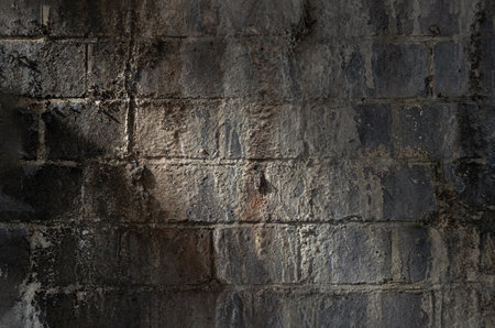 An old stained brick wall background with traces of time. Dark brick concrete blocks wall grunge texture, use it as your Wallpaper, Poster and Space for text, Selective focus.の写真素材