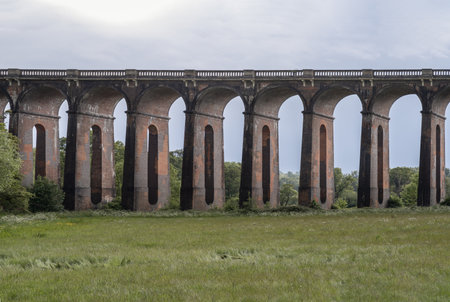 Sussex, UK - May 21, 2025 - Architectural splendour of Ouse Valley Viaduct or Balcombe Viaduct (Railway viaduct) with sky background, carries the Brighton Main Line over the River Ouse in Sussex, has been described as âthe most elegant viaduct in Britainâ, The semi-circular arches vaulting supporting brick piers, composed of traditional red bricks topped with smooth limestone. use it as your Wallpaper, Poster and Copy space, Selective focus.の写真素材