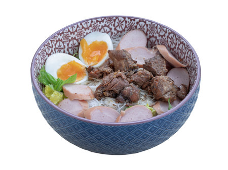Dry rice vermicelli noodles (thin rice noodles) with cutting sausage, boiled egg and braised pork (stewed pork) and vegetables in ceramic bowl isolated on white background.の写真素材
