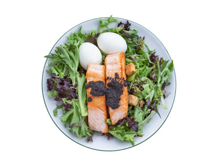 Top view of Homemade salad with Grilled salmon fillets, Boiled egg and Croutons topping Caviar on plate isolated on white background with clipping path, Simple yet very tasty dish.の写真素材