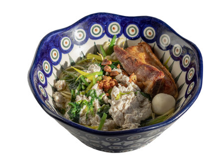 Egg noodles soup served with Crispy pork belly, Fish balls, Minced pork, Cantonese kale and Mung bean sprouts sprinkled with pork crackling, Fried garlic in ceramic bowl isolated on white background with clipping path. Selective focus.の写真素材
