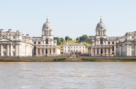 London, UK - Jun 18, 2025 - A stunning view of the iconic twin-domed buildings of the Old Royal Naval College, with the Queen's House situated between them, Beyond the Queen's House, visible on the hill in Greenwich Park, is the Royal Observatory. and the River Thames in the foreground, as viewed from Island Gardens. use it as your Wallpaper, Poster and Space for text, Selective focus.の写真素材
