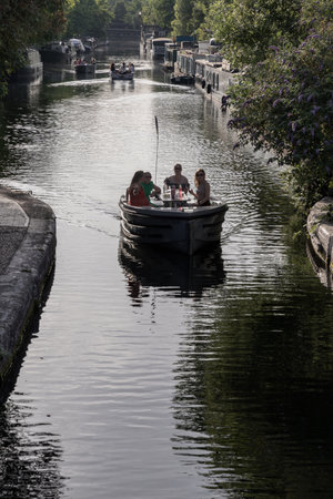 London, UK - Jun 21, 2025 - Tourist are relaxing on a Waterdream boat in Little Venice in West London at evening, It is the junction point of the Grand Union Canal and the Regent's, its tranquil canals and waterways lined with narrowboats and houseboats. use it as your Wallpaper, Poster and Copy space, Selective focus.の写真素材