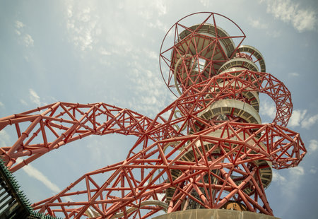 London, UK - Jun 21, 2025 - Looking up view of ArcelorMittal Orbit and features Red lattice structure with a Spiral slide, known as the Helix, Observation tower located in Queen Elizabeth Olympic Park in Stratford, use it as your Wallpaper, Poster and Space for text, Selective focus.の写真素材