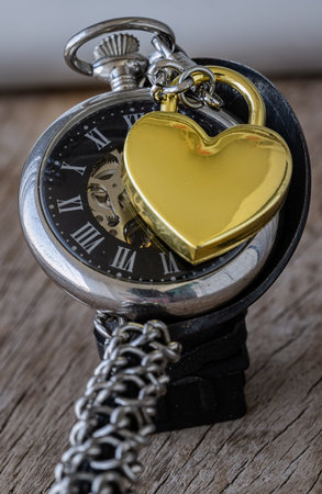 A gorgeous of Golden heart shaped love padlock on A retro pocket watch. Love can endure beyond the...