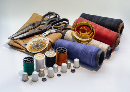 Steel scissors and Pins in small round tray on Sackcloth with Measuring tape on Spools of thread of...