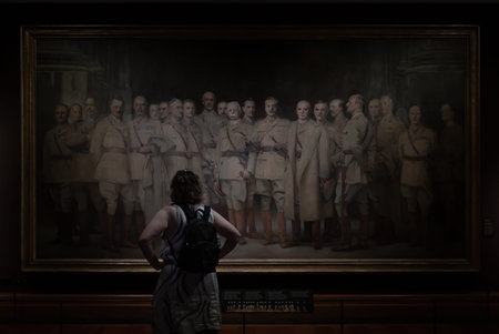 London, UK - Jul 12, 2025 - A person wearing a backpack is observing a large painting. The painting...