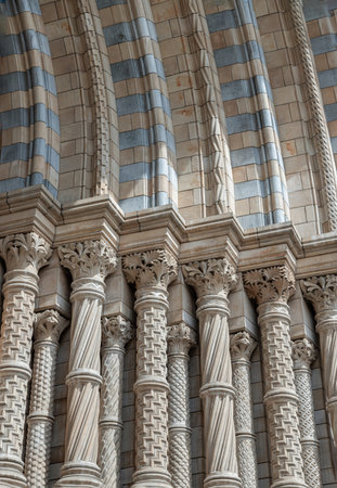 London, UK - Jul 21, 2025 - Tiled archway and pilasters at the main entrance of the Natural History Museum in London. the intricate design of the pilasters and the distinctive tiling of the archway, characteristic of the museum's Romanesque Revival architecture, use it as your Wallpaper, Poster and Copy space, Selective focus.の写真素材