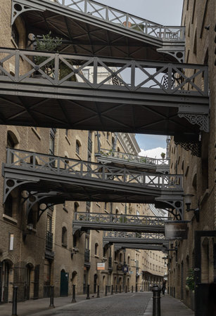 London, UK - Jul 21, 2025 - View along the iconic street of Shad Thames and features Victorian-era warehouse architecture, including the historic cobbled street, brick construction and the overhead walkways or gantries connecting the warehouse apartments of Butlers Wharf. many of these buildings have been converted into residential apartments and commercial spaces, preserving their exterior architectural integrity while adapting them for modern use, Copy space, Selective focus.の写真素材
