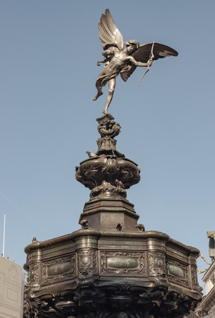 London, UK - May 13, 2025 - The Statue of Eros is The Greek god anteros (the Greek God of love)â that sits atop of the Shaftesbury memorial fountain is bronze on blue sky background, is a cast aluminium sculpture with winged poised in Piccadilly circus. use it as your Wallpaper, Poster and Copy space, Selective focus.の写真素材