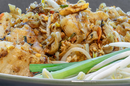 Close-up of Traditional fried thai noodle (pad thai) mix Stirred fried turnip cake or Fried radish cake (chai tow kway) served with bean sprout and chives in ceramic plate. use it as your Copy space, Design, Wallpaper and Poster, Selective focus.の写真素材