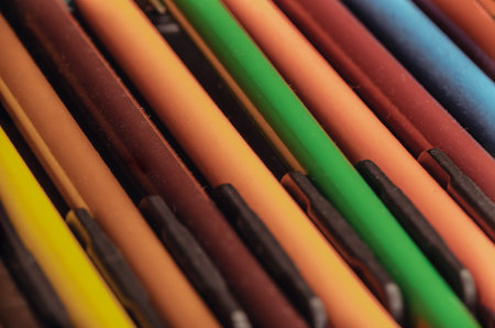 Close-up of multi colored pencils or wooden crayons to each other arranged in a neat row in wooden pencil case. The arrangement of the colors pencils creates a sense of unity. Pencils made of natural eco-friendly materials safe for children, Stationery for drawing and creativity, Empty space for text, design and wallpaper, Selective focus.の写真素材